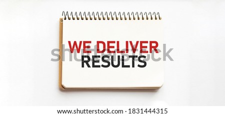 Notepad with text WE DELIVER RESULTS. White background. Business