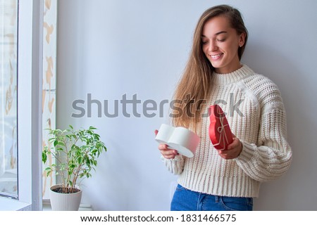 Cute smiling happy charming beloved woman received a gift for february 14 and opens a heart shaped box for valentines day. Copy space 