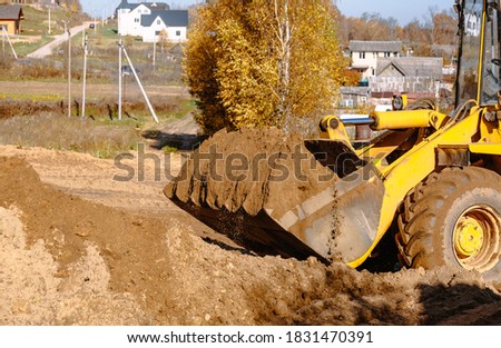 large yellow wheel loader aligns a piece of land for a new building. Preparation of the land for the auction. Leveling the landscape and adding sand for construction. Banner wallpaper.