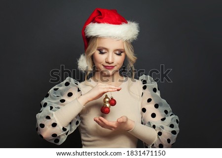 Attractive woman Santa holding Xmas balls on black background. Christmas holiday and New Year party portrait