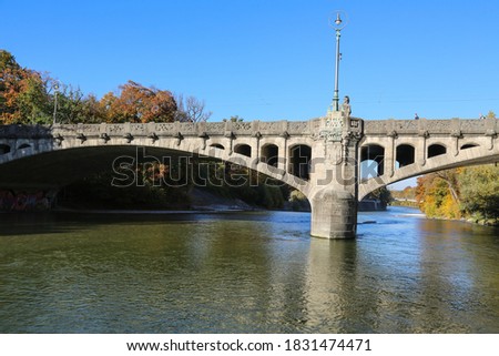 The historic Maximiliansbrücke - an arched bridge over the Isar river in Munich Germany in fall