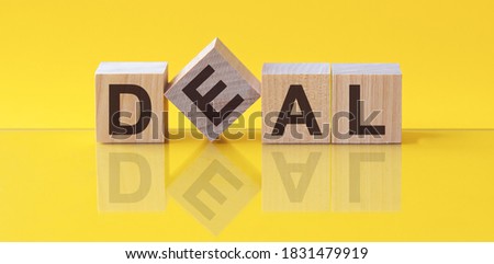 Deal word written on wood block. corporate text on table, concept. Word Deal is made of wooden building blocks lying on the table and on a light yellow background.