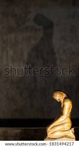 A  close-up frame of the illuminated wooden sculpture of prayer with a great shadow on the background.