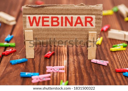Webinar. Text WEBINAR on paper on wooden background with many colorful clothespins. Concept of seminar or other presentation types that conducted using the Internet.