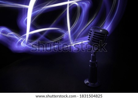 Retro style microphone on background with backlight. Vintage silver Microphone for sound, music, karaoke. Speech broadcast equipment. Live pop, rock musical performance. Selective focus