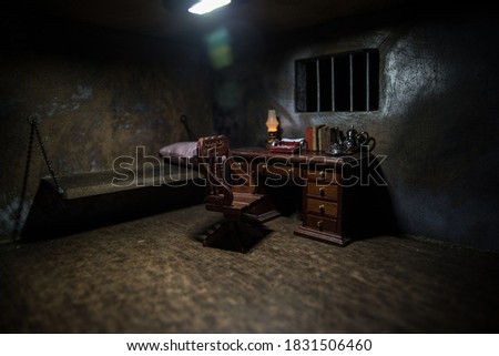 Man in prison man behind bars concept. Old dirty grunge prison miniature. Dark prison interior creative decoration. Miniature table inside. Selective focus