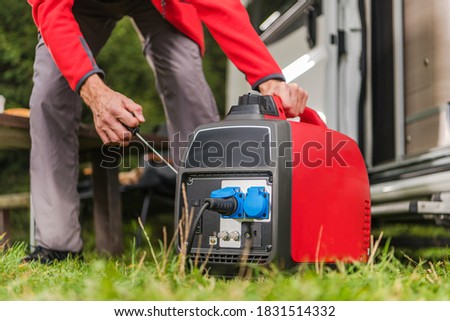 Caucasian Men in His 40s Firing Up Gas Powered Portable Inverter Generator To Connect Electricity To His Camper Van.  Royalty-Free Stock Photo #1831514332