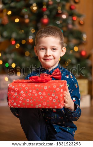 Christmas fabulous, little boy holding a big red box with a present from Santa.