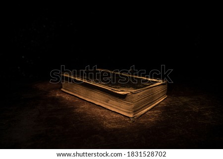 A stack of old books. Vintage book on wooden table. Magic lightning around a glowing book in the room of darkness. Selective focus Royalty-Free Stock Photo #1831528702