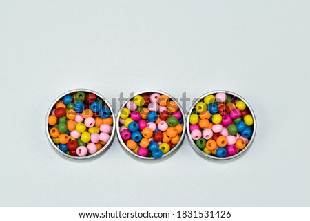 Colorful wooden beads in metal containers.