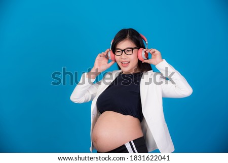 Beautiful pregnant Asian woman listening to music from
Headphones comfortably On a ฺBule background , Expectation of young mothers, pregnancy pictures and childbirth