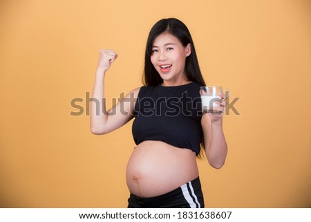 Beautiful pregnant woman, Asian drinking milk On a yellow background, the expectation of a young mother, pregnancy and childbirth pictures.