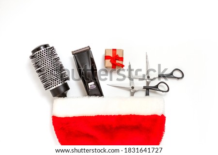 Christmas composition. Hairdressing tools in a Santa Claus hat on a white background. Template for a postcard or information about a hair salon. Flat lay, copy space.