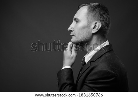Portrait of businessman in suit against gray background