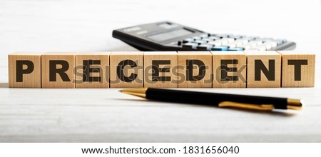 The word PRECEDENT is written on wooden cubes between the calculator and the pen. Business concept.