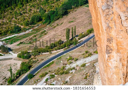 A rural road in the middle of rolling green valley photographed from above from a cliff