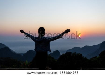 Back view of a happy female tourist watching the sunset