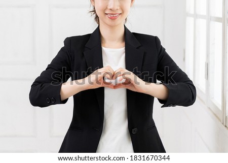 A young business woman who makes a heart shape with her hands shot in the studio