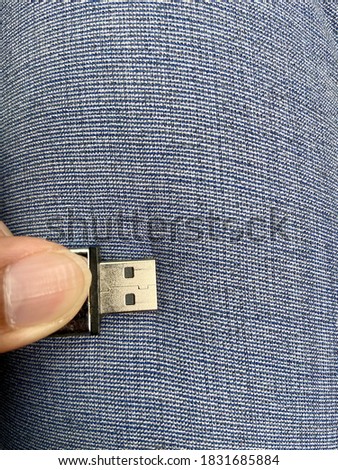 A hand holding USB drive flash drive with empty copy space of long sleeve pant cloth as a background