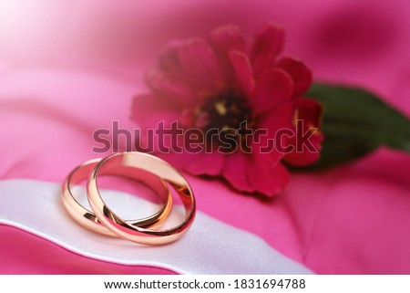 wedding rings and pink flower so close