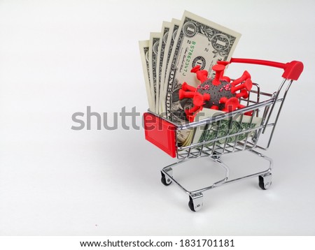 On a white background, a grocery shopping cart containing one dollar bills and a model of a coronavirus cell.  Concept: economic crisis due to the worldwide Covid-19 pandemic