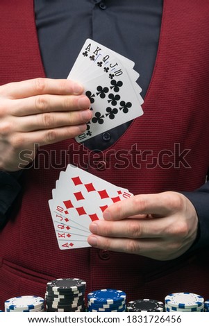 the dealer's hands are holding a red and black combination of winning cards