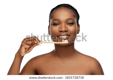 beauty and people concept - close up of of happy smiling young african american woman cleaning teeth with wooden toothbrush over white background