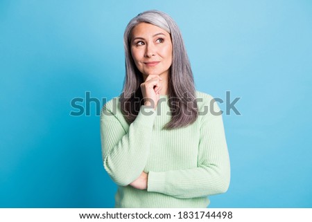 Photo of minded pensive old lady touch chin hand look copyspace think thoughts isolated over blue color background