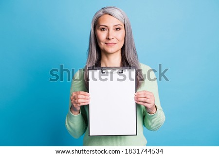 Photo portrait of woman holding clipboard with blank space in two hands isolated on pastel light blue colored background