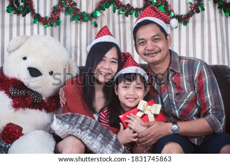 Asian family in Christmas interior.Happy mother father and  daughter holding a gift box with smile