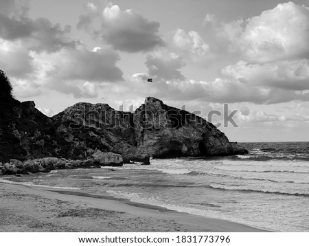 black and white photo of rocky peninsula blue sky and undulating sea view