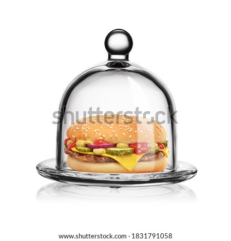 Classic cheeseburger in transparent glass bell jar isolated on white background.