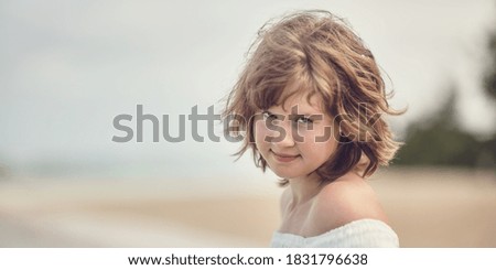 Portrait of a shaggy girl from the sea wind with a blurred background at a shallow depth of field