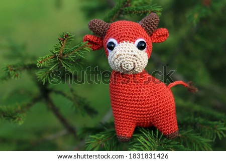 Knitted toy goby on fir branches, New Year greeting card. Chinese Year of Bull, Zodiac symbol 2021
