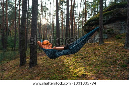Halloween Scarecrow with a carved pumpkin in relax in Hammocks on trees in the forest it seems they are planning something indecent. Gloomy forest. An ideal image for fall, halloween.
