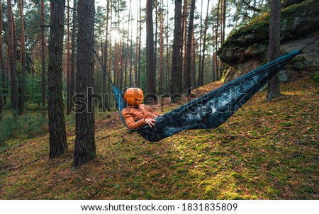 Halloween Scarecrow with a carved pumpkin in relax in Hammocks on trees in the forest it seems they are planning something indecent. Gloomy forest. An ideal image for fall, halloween.

