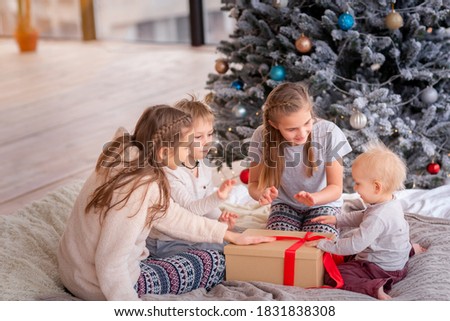 Happy kids having fun and opening presents near christmas tree.