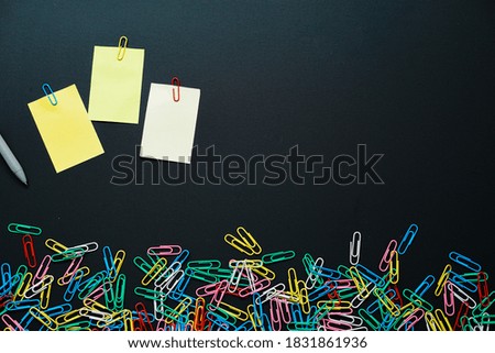 colorful of paper clips and colorful empty notepad stick on black board, copy space concept.