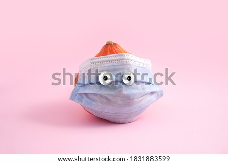 Pumpkin with medical face mask and funny eyes. Pink background, creative minimal concept