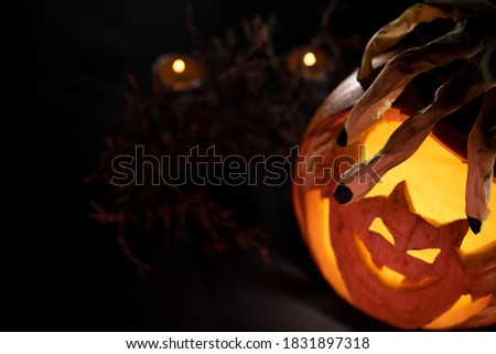 bat carved pumpkin with skeleton hand and candles