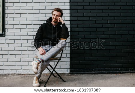 City portrait of charismatic hipster guy wearing black blank hoodie with space for your logo or design. Mockup for print