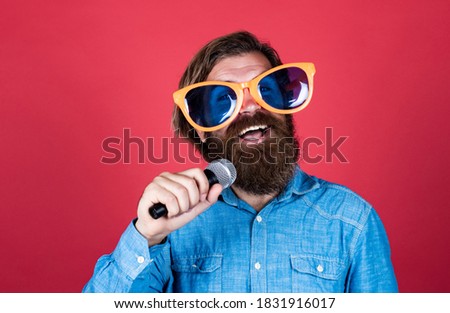 party goer. hipster man with beard wearing glasses. music concept. have a happy holiday. have fun on party. male singer singing song in microphone. celebrate the anniversary.