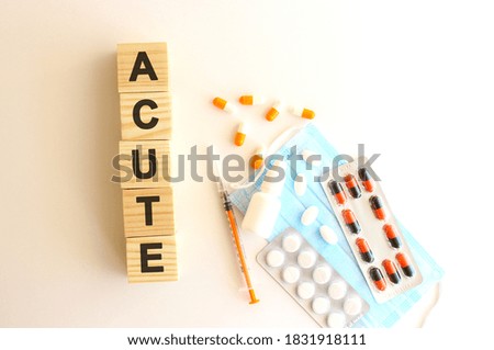 The word ACUTE is made of wooden cubes on a white background with medical drugs. Medical concept.