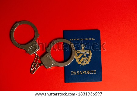 Cuban passport with handcuffs on red background Royalty-Free Stock Photo #1831936597