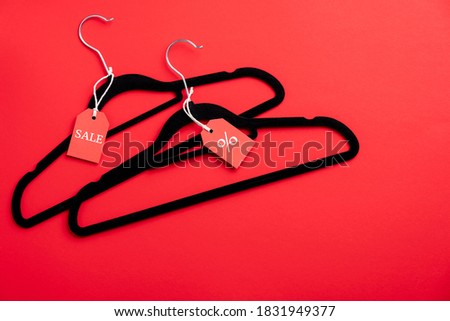 Two coat hangers on red background. Flat lay, top view. Black Friday sale, discount, outlet in fashion store concept.