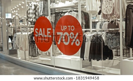 White text on the red sticker on the glass of window in the store with the inscription sale up to 70% off