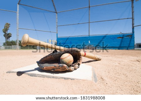 A baseball bat, glove and ball lie on top of home plate as a conceptual sports image. Royalty-Free Stock Photo #1831988008