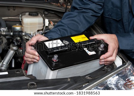 A car mechanic replaces a battery during maintenance. Royalty-Free Stock Photo #1831988563