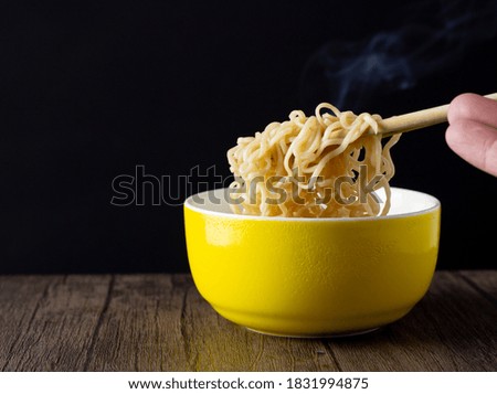The picture of the breakfast is a bowl of noodles with chopsticks and a smoke or steam. It is the instant meal of the Asian people it is the fast cooking of the restaurant the background is black.