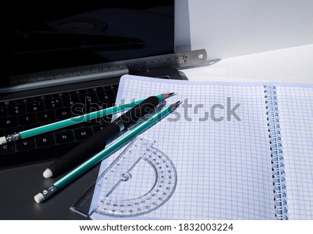  Office supplies on laptop keyboard. Ruler Pencils protractor ballpoint pen and squared notebook. A universal template for the announcement of a text message on the topic of study and work.